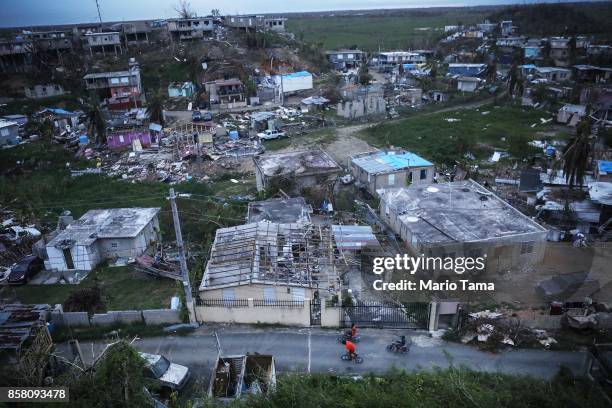 Kids bike in an area without grid power or running water about two weeks after Hurricane Maria swept through the island on October 5, 2017 in San...