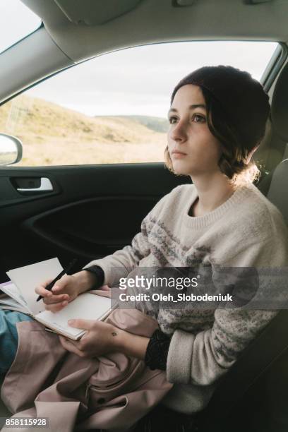 woman writing in travel journal in car - knitted car stock pictures, royalty-free photos & images
