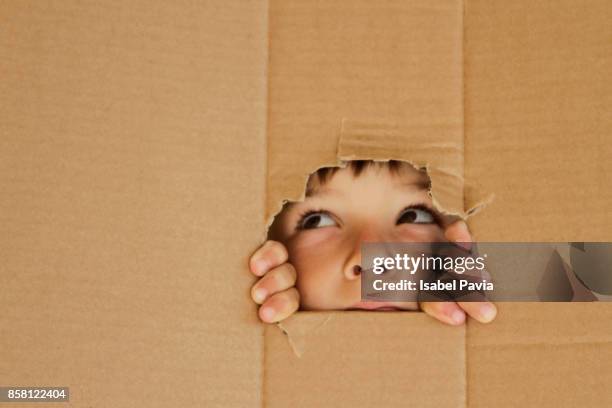 boy looking up through a hole on cardboard - eye catching stock pictures, royalty-free photos & images