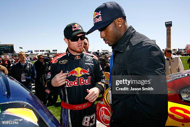 Brian Vickers , driver of the Red Bull Toyota, talks with running back Reggie Bush of the New Orleans Saints on the grid prior to the start of the...