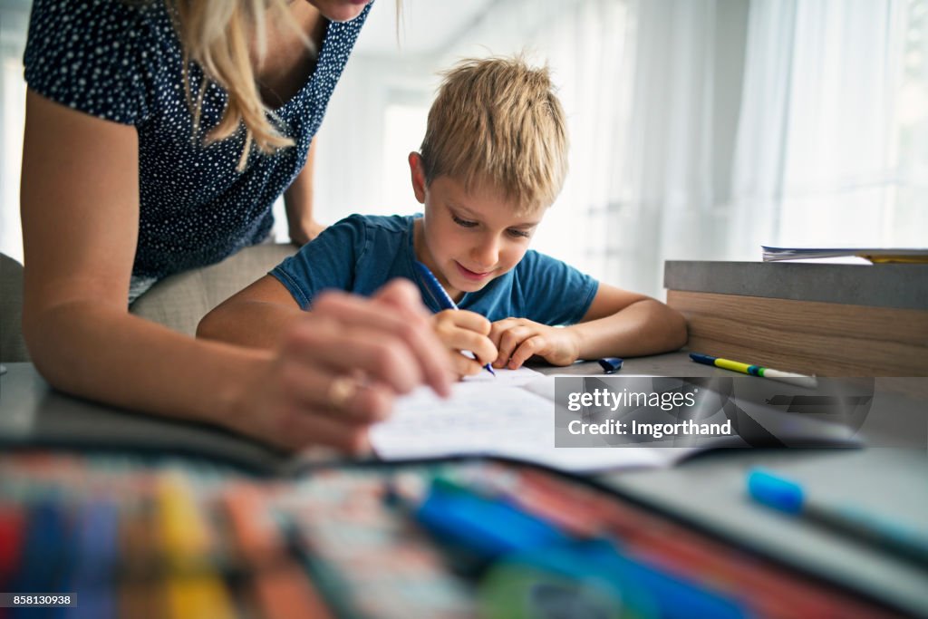 彼の宿題をする母を助ける息子