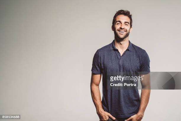 smiling man standing with hands in pockets - fotografia de três quartos imagens e fotografias de stock