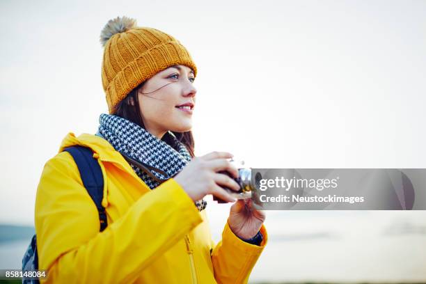 mooie jonge wandelaar die houdt van vintage camera tegen heldere hemel - geel jak stockfoto's en -beelden