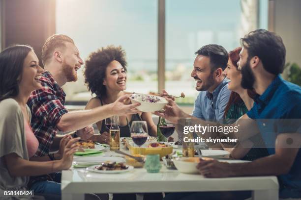 large group of cheerful friends having fun while eating lunch together. - large dinner party stock pictures, royalty-free photos & images