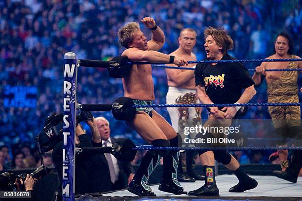 Former professional wrestlers Ric Flair looks on as WWE Superstar Chris Jericho gets pummeled on the ropes by "Rowdy" Roddy Piper. Ricky "The Dragon"...