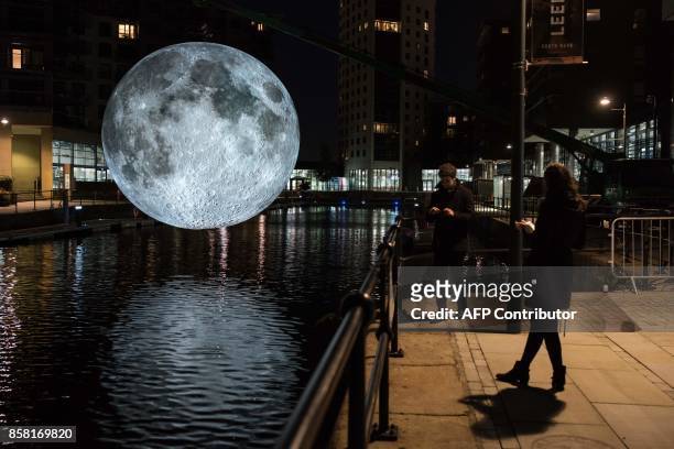 Members of the public admire an illuminated art installation entitled 'Museum of the Moon' which features in the annual 'Light Night Leeds' festival...