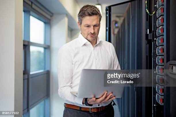 adult male technician manager working in server room setting - computer network technician stock pictures, royalty-free photos & images