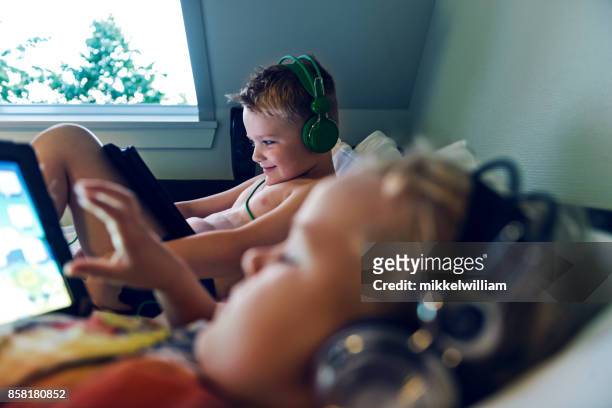 es ist schlafenszeit, aber zwei kinder beobachten inhalte auf ihre digitalen tabletten vor dem schlafengehen - dänemark gemütlich stock-fotos und bilder