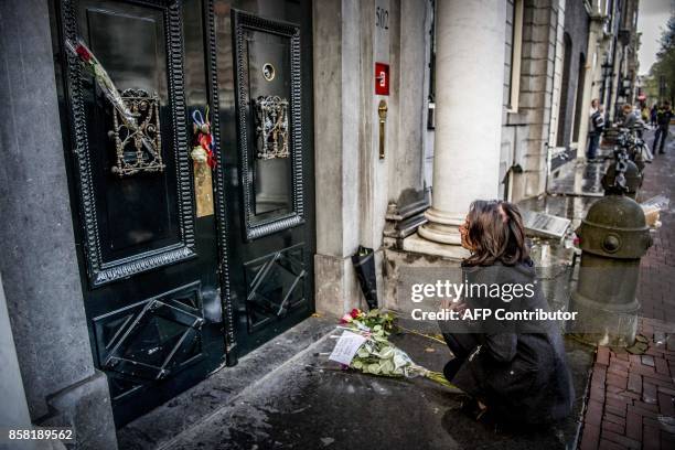 Woman kneels near flowers placed in front of the office of late Amsterdam mayor Eberhard van der Laan in Amsterdam on October 6, 2017. Eberhard van...