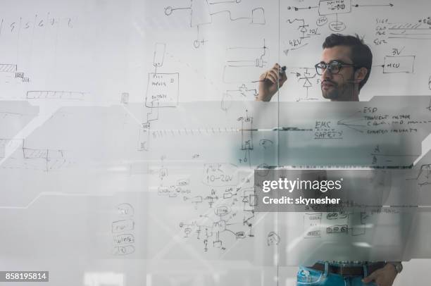 männliche ingenieur arbeitet an neuen ideen und schreibt diagramm an glaswand. - complexity stock-fotos und bilder
