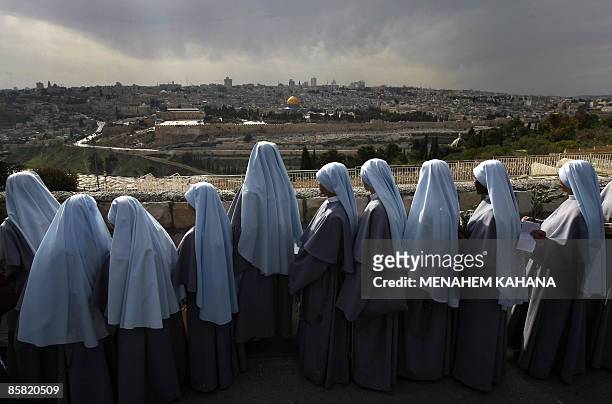 Catholic nuns take part in the traditional Palm Sunday procession from Mt. Olives to Jerusalem's old city as the golden Dome of the Rock appears in...