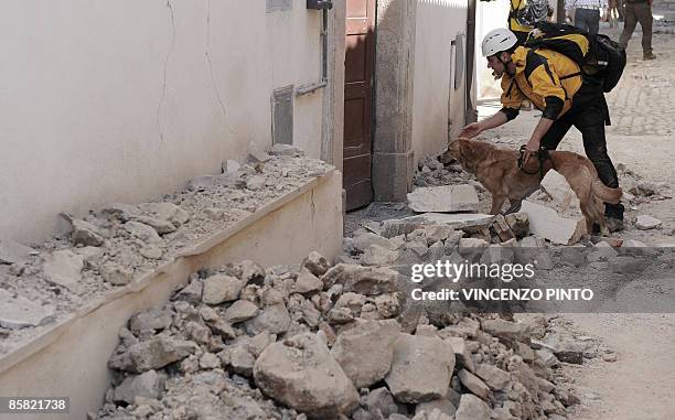 Rescuer follows his dog on April 6, 2009 at the entrance of a house which partly collapsed in Onna, a small town some 10 kilometers from L'Aquila,...