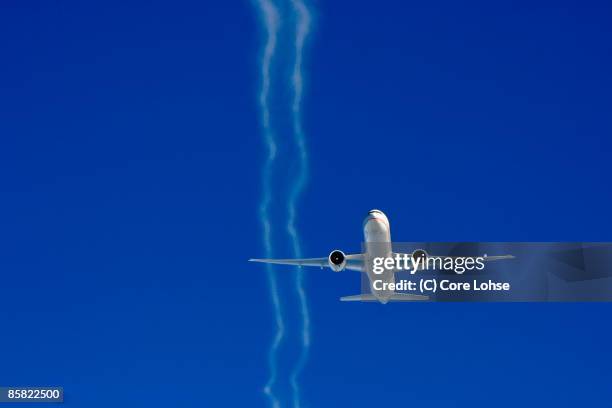 etihad boeing 777 with contrails on blue  - boeing photos et images de collection