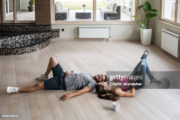 young happy couple relaxing on a parquet floor at their new apartment. - parquet floor stock pictures, royalty-free photos & images