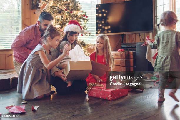 ferienzeit: familie schmücken den weihnachtsbaum - present unwrap stock-fotos und bilder