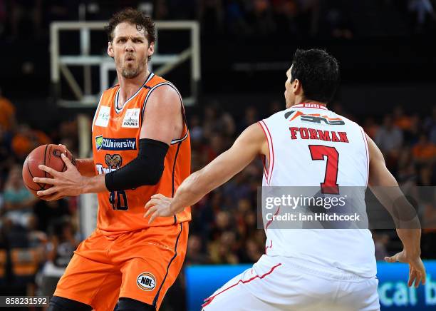 Alex Loughton of the Taipans looks to pass the ball past Oscar Forman of the Hawks during the round one NBL match between the Cairns Taipans and the...