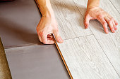 handyman's hands laying down laminate flooring boards