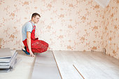 handyman laying down laminate flooring boards