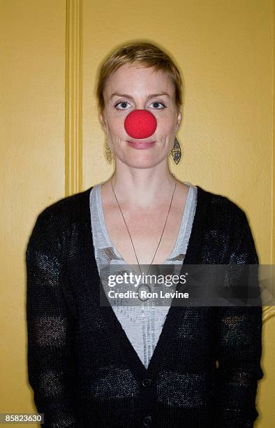 woman wearing red clown nose, portrait - clownsneus stockfoto's en -beelden