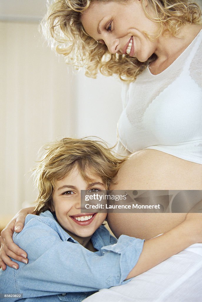 Smiling Kid Embracing His Pregnant Mother Belly High-Res Stock Photo
