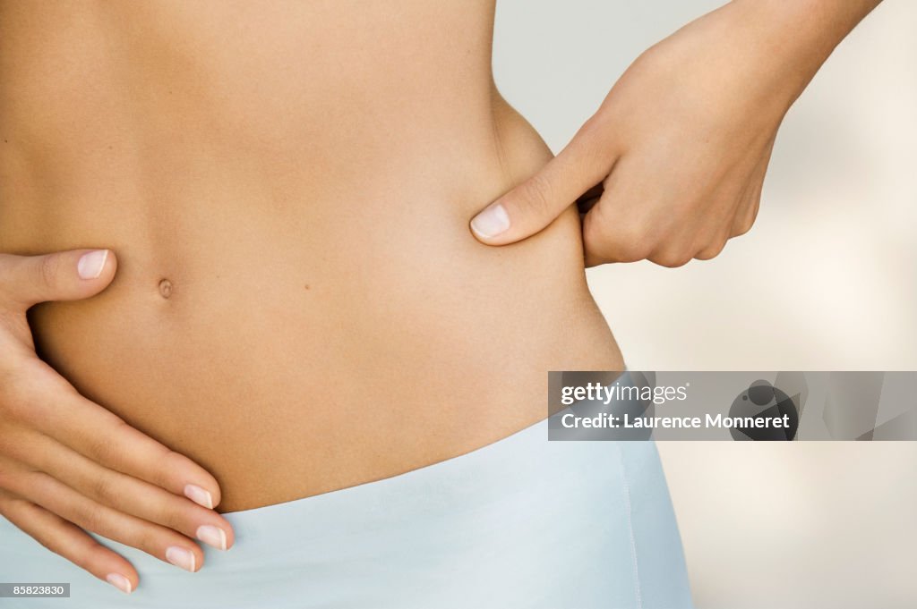 Closeup on a young woman pinching her waist