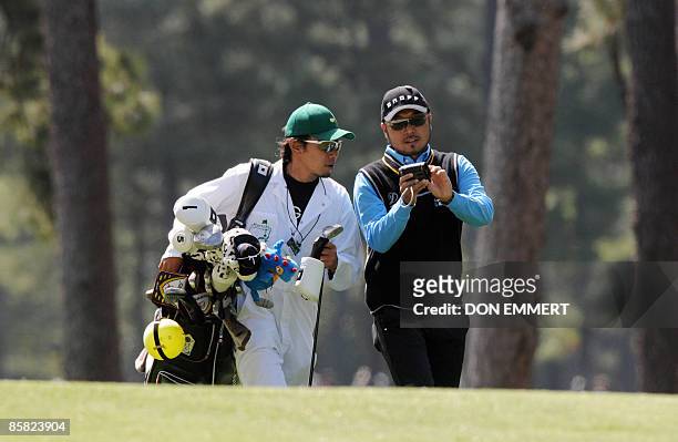 Shingo Katayama of Japan takes a yardage meter from his caddy while walking down the number one fairway during a practice round April 6, 2009 at the...