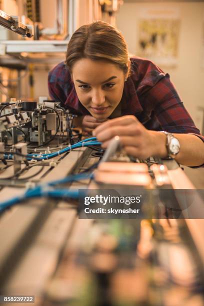 studente ingegnere sorridente che esamina parte della linea di produzione in laboratorio. - studentessa di scuola secondaria foto e immagini stock