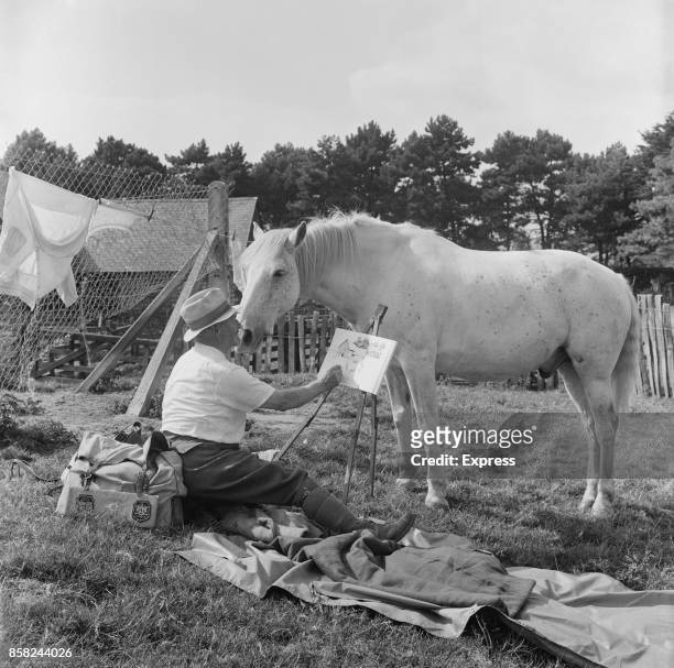 Artist and writer William Holt paints next to his horse named Trigger, UK, 31st August 1964.