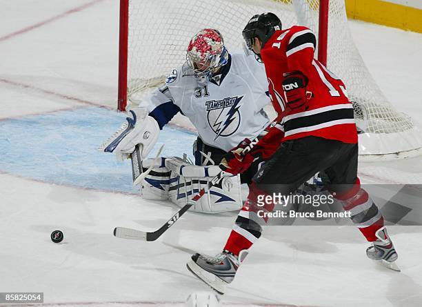 Karri Ramo of the Tampa Bay Lightning makes the stop on Travis Zajac of the New Jersey Devils on April 3, 2009 at the Prudential Center in Newark,...