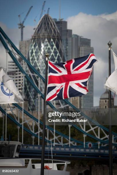 The Union Jack flag flies in the foreground of Tower Bridge and construction work in progress next to the Swiss Re Building in the capital's...