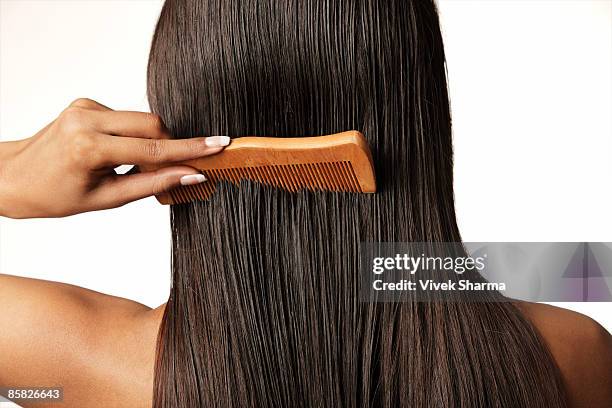 woman pulling comb through her hair - woman pulling hair back stock pictures, royalty-free photos & images