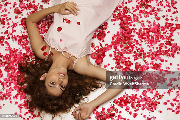 woman lying surrounded by rose petals - rose pedals bed stock pictures, royalty-free photos & images