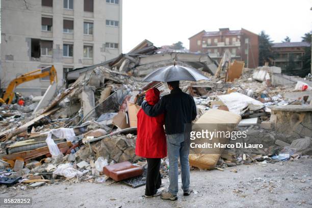 Two residents stand under an umbrella as they look at the ruins of their home after an earthquake on April 6, 2009 in L'Aquila, Italy. The 6.3...