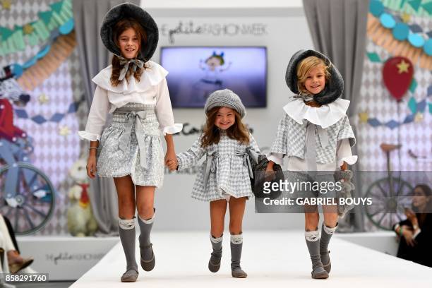 Three girls, including one with Down Syndrome, present creations on the catwalk during "The Petite Fashion Week" in Madrid on October 6, 2017. - Some...