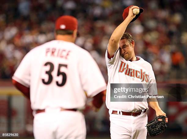 Starting pitcher Brandon Webb of the Arizona Diamondbacks wipes up his face as pitching coach Bryan Price approaches the mound during the MLB...