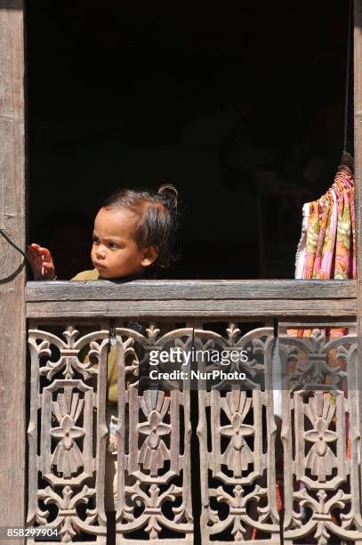 Little kid observing festival as Locals carry as well as rotates top part of a chariot of Lord Narayan across the streets of Hadigaun during Lord...