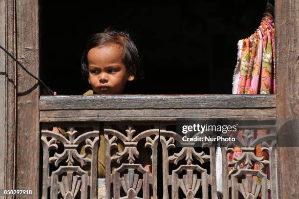 Little kid observing festival as Locals carry as well as rotates top part of a chariot of Lord Narayan across the streets of Hadigaun during Lord...