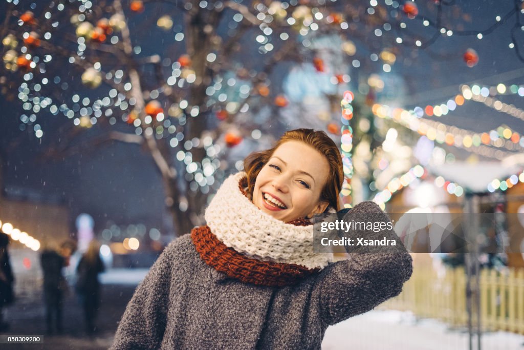 Glückliche Frau auf dem Weihnachtsmarkt in der Nacht
