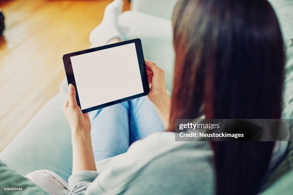 Woman with brown hair holding digital tablet at home