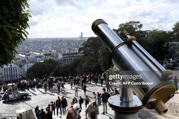 Tourists enjoy the view from the Sacre-Coeur forecourt at the top in the Montmartre district of Paris on October 6, 2017. / AFP PHOTO / STEPHANE DE...