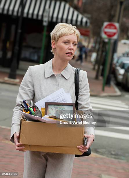 laid off woman carrying box of possessions - rauswerfen stock-fotos und bilder
