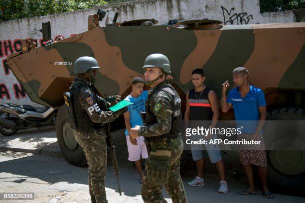 Residents of Morro dos Macacos favela wait to be searched by Brazilian Armed Forces soldiers during a security operation in the area in Rio de...