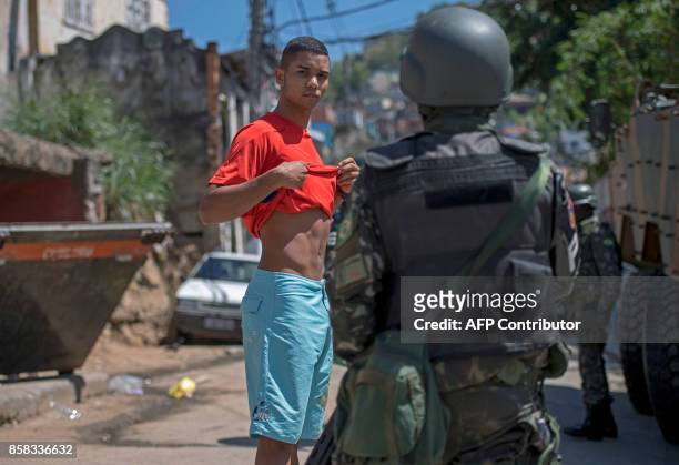 Young resident of Morro dos Macacos favela is searched by a Brazilian Armed Forces soldier during a security operation in the area in Rio de Janeiro,...