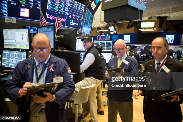 Traders work on the floor of the New York Stock Exchange in New York, U.S., on Friday, Oct. 6, 2017. U.S. Stocks edged lower while the dollar rose...
