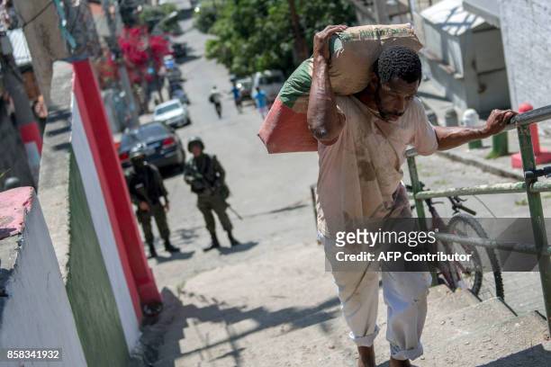 Resident of Morro dos Macacos favela carries a bag of cement after Brazilian soldiers frisked him during a security operation in the area in Rio de...