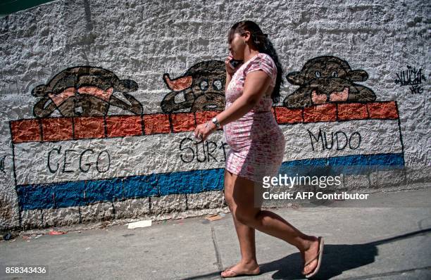 Resident of Morro dos Macacos favela walks past a graffiti reading "blind, deaf, dumb" during a security operation in the area in Rio de Janeiro,...