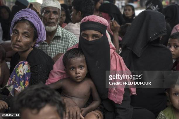 Rohingya Muslim refugee takes shelter from the rain at the registration center in Teknaf in Bangladesh's Ukhia district on October 6, 2017....
