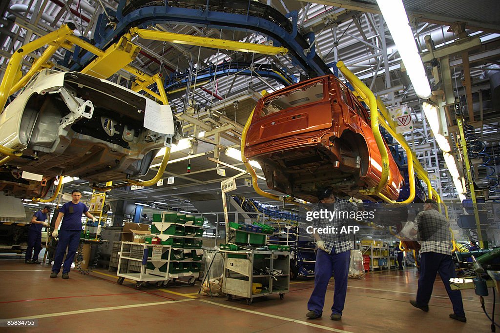 Employees work on a car assembly line pr