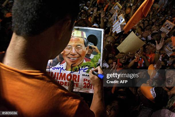 Kenyi Fujimori, son of Peru's former President Alberto Fujimori, signs an autograph on a poster of his father during a rally in support of him...