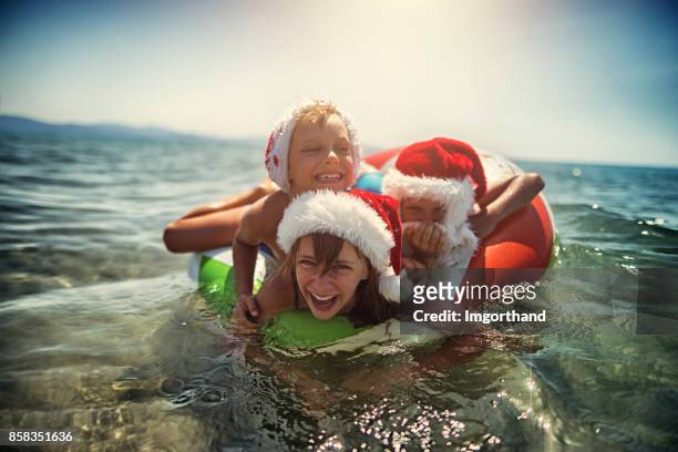 kinderen spelen in zee op zwemmen ring zomers kerst - santa swimming stockfoto's en -beelden